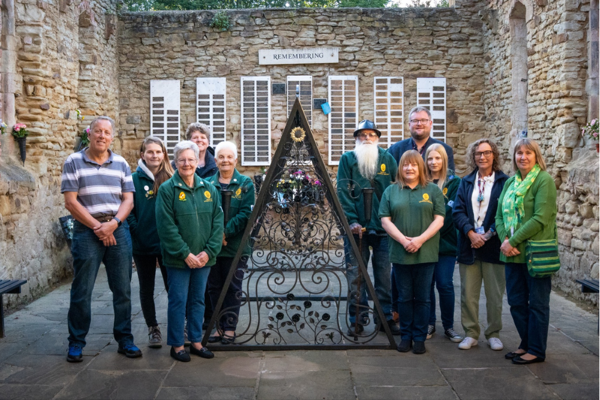 A Group Of People Stood By A Metal Frame Umbraco
