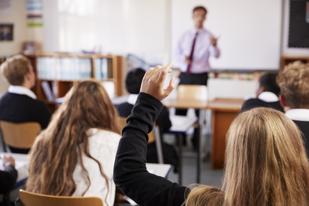 Secondary school classroom: pupil with hand up
