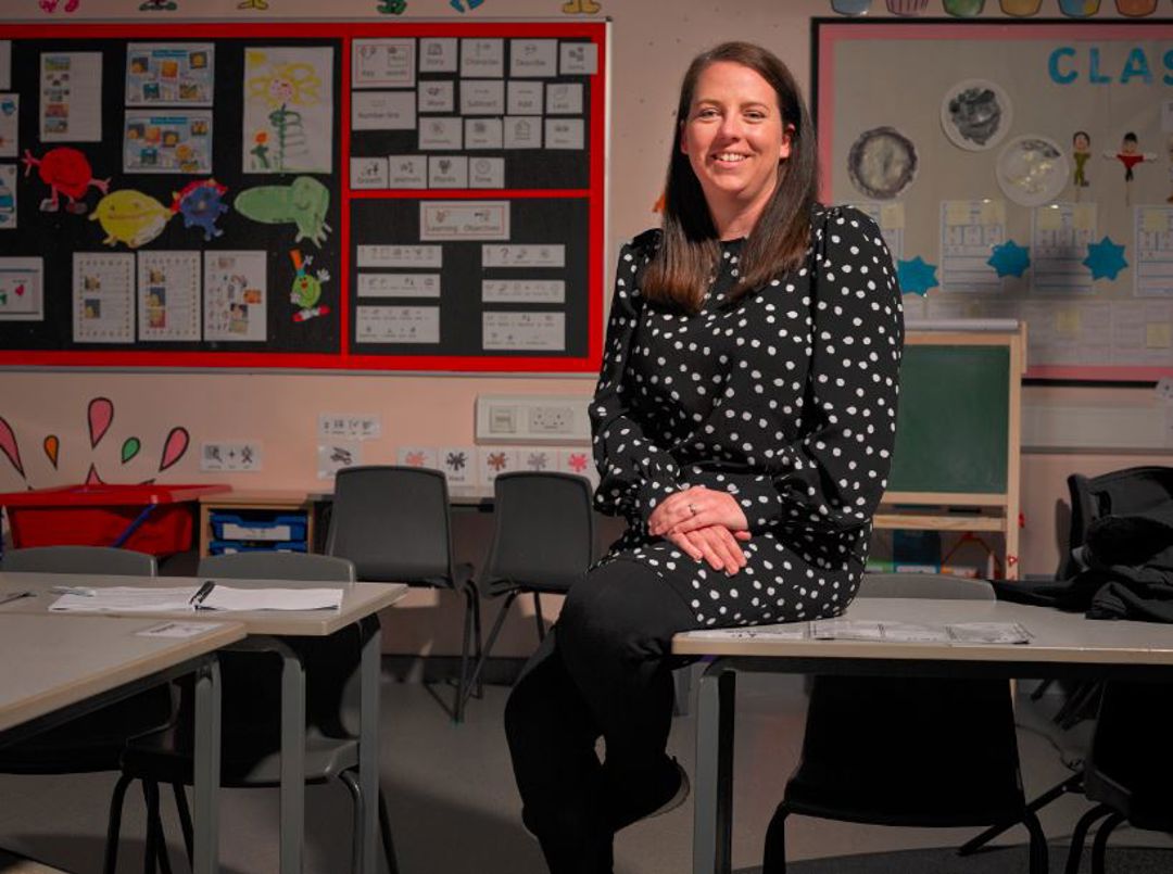 Teacher Lisa sitting on a desk