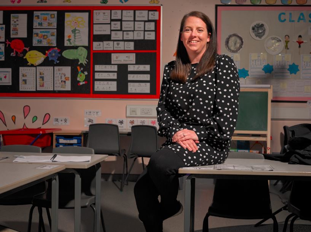 Teacher Lisa sitting on a desk