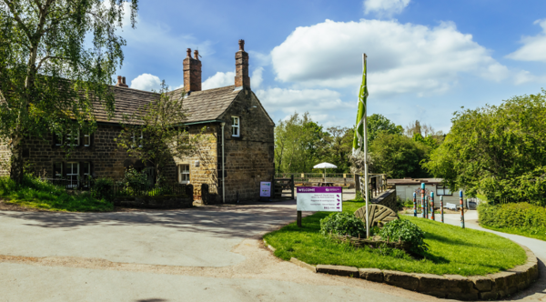 The front entrance to Worsbrough Mill with a purple welcome sign that has directions on it for visitors