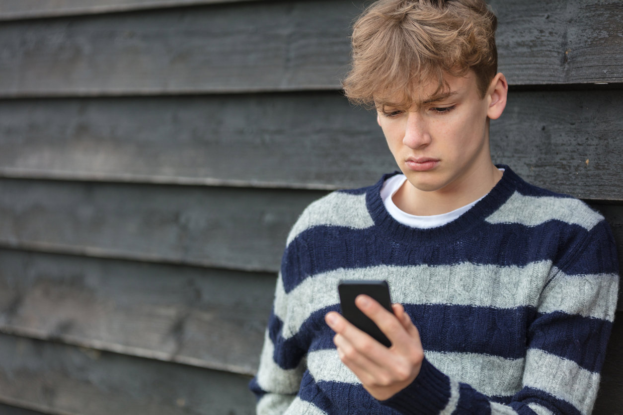Thoughtful teenager looking at smartphone