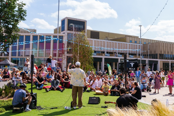 A Crowd Watches A Live Music Performance In The Glass Works Square