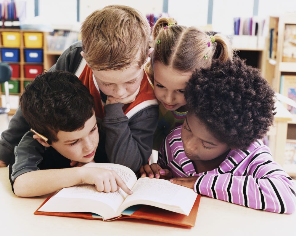 Group of young children looking at a book
