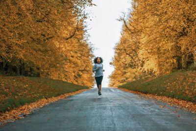 Woman running through a park in autumn