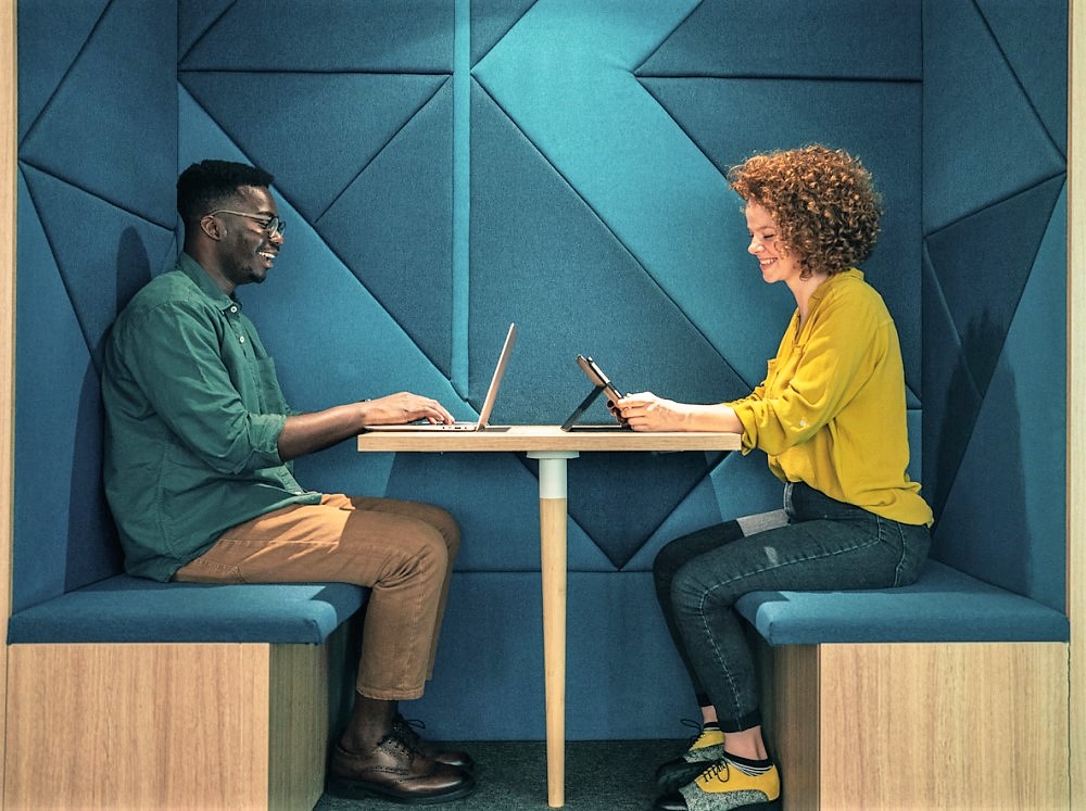 People sat in office booth working on laptops