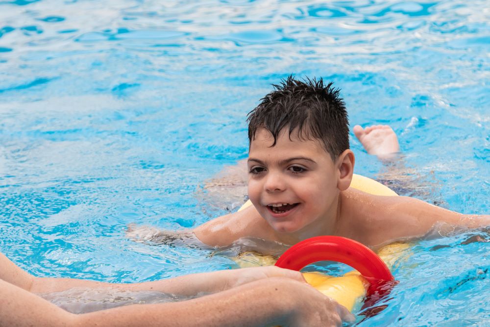 Disabled boy floating in swimming pool
