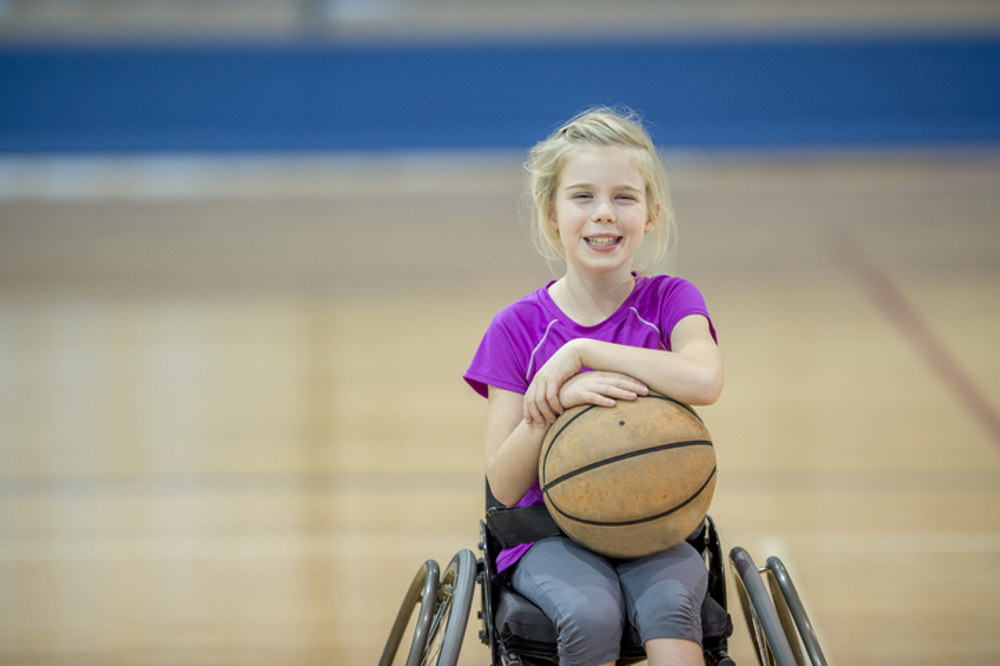 Girl in wheelchair holding basket ball
