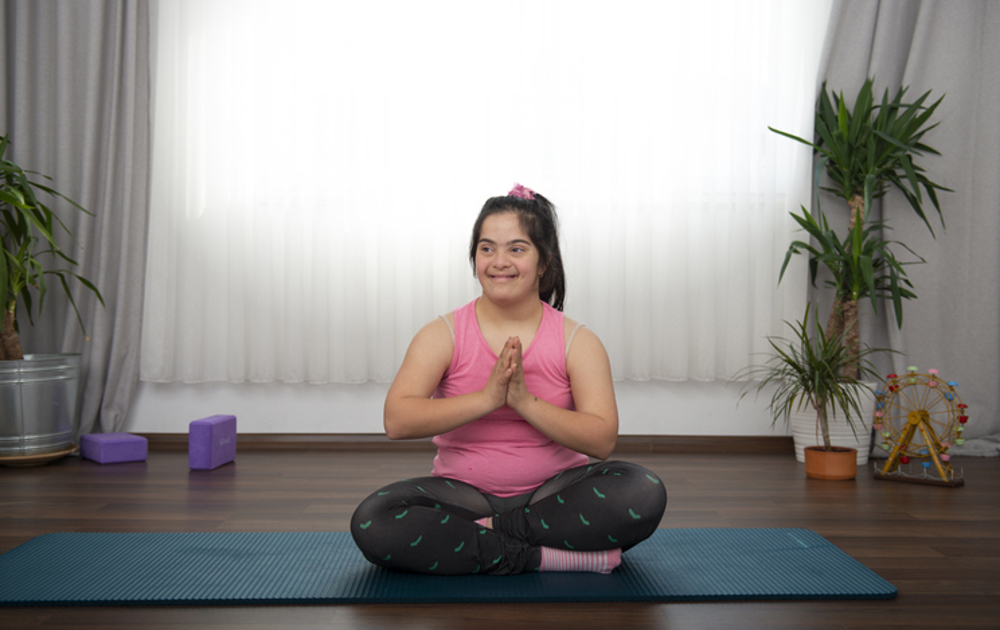 Girl with down syndrome sat on yoga mat