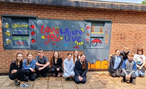 A Group Of Students With A New Mural Showing The Words Love Where You Live And Nature