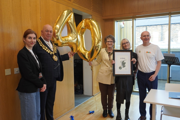 A group of people standing with a 40 balloon in celebration of DIAL's anniversary