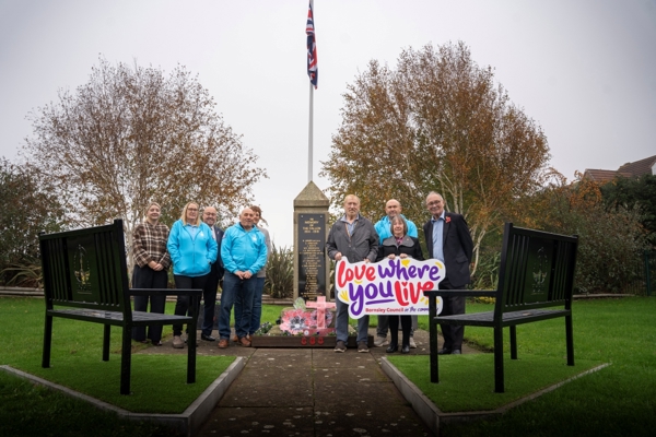 A Group Of Men And Women Beside A War Memorial With A Bench On Either Side