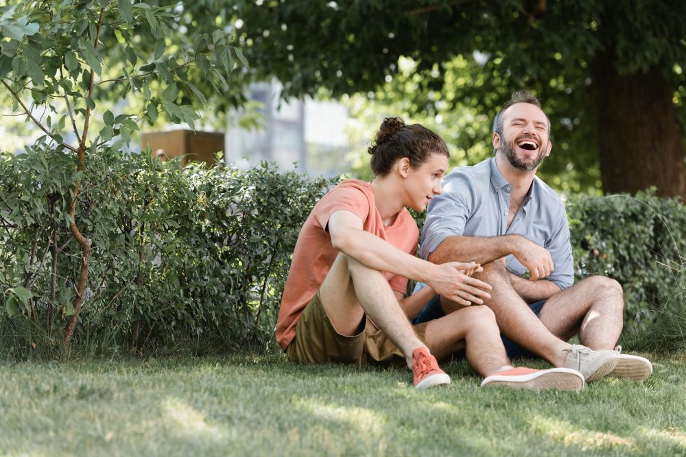 Foster Carer And Teenage Boy Sat On The Grass