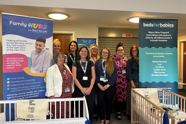 Family Hubs team stood with representatives from the South Yorkshire Mayoral Combined Authority and Baby Basics UK, stood in front of Beds for Babies free bed options