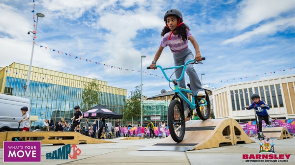 A Girl Riding A Bicycle In The Glass Works Square