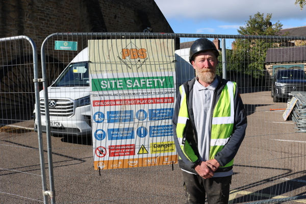 Man In High Vis And Helmet Stands In Front Of Safety Signage And Fence At Elsecar Heritage Centre