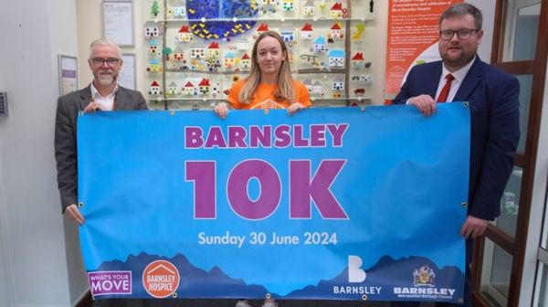 Cllr and hospice staff holding a Barnsley 10k banner