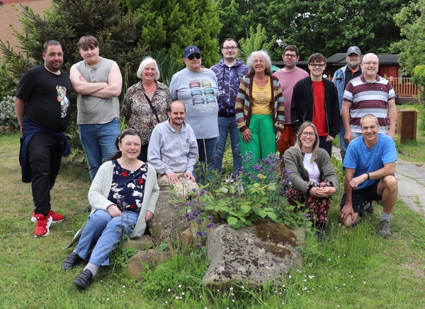 A Group Of People Gathered Around Plants In A Rockery
