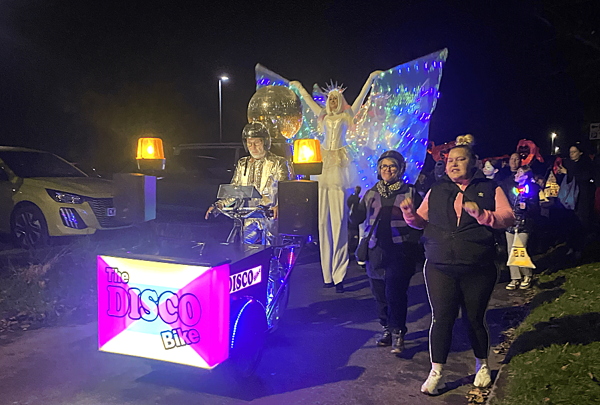 People Holding Lanterns In A Parade Led By A Disco Bike (1)