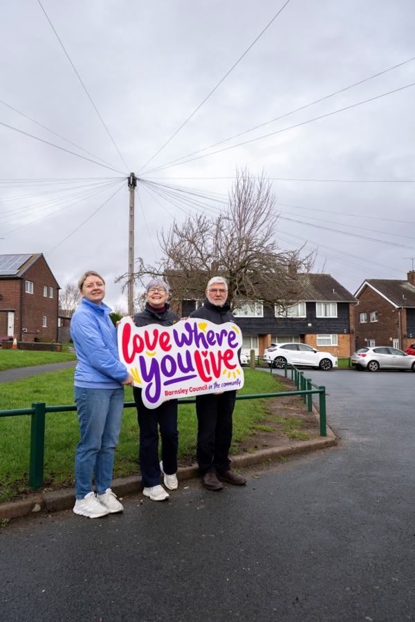 Two Women And A Man Holding A Sign Saying Love Where You Live