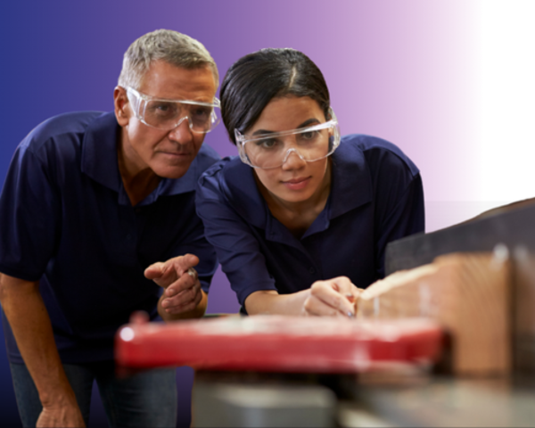 Image of tutor and an apprentice wearing goggles and working on woodwork