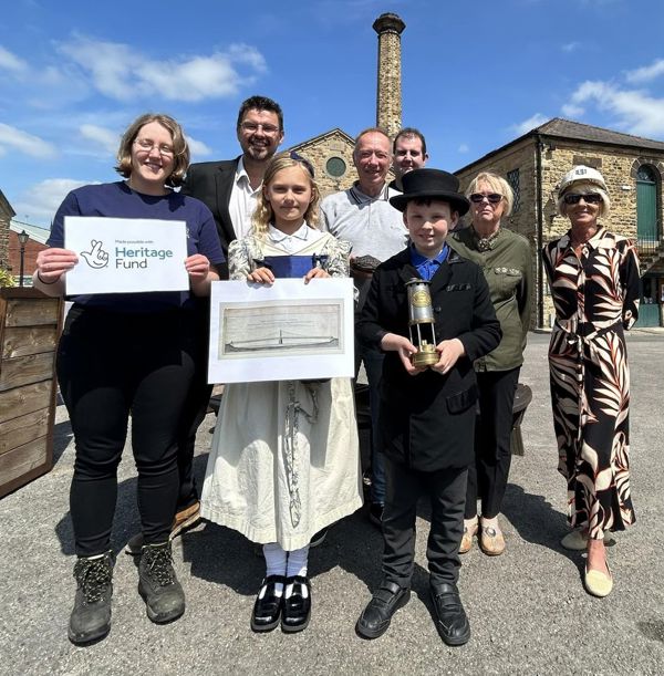 Adults at Elsecar Heritage Centre with two children who're dressed in old fashioned clothing